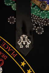 Poker chips, a watch, and a card with a decorative logo on a black background